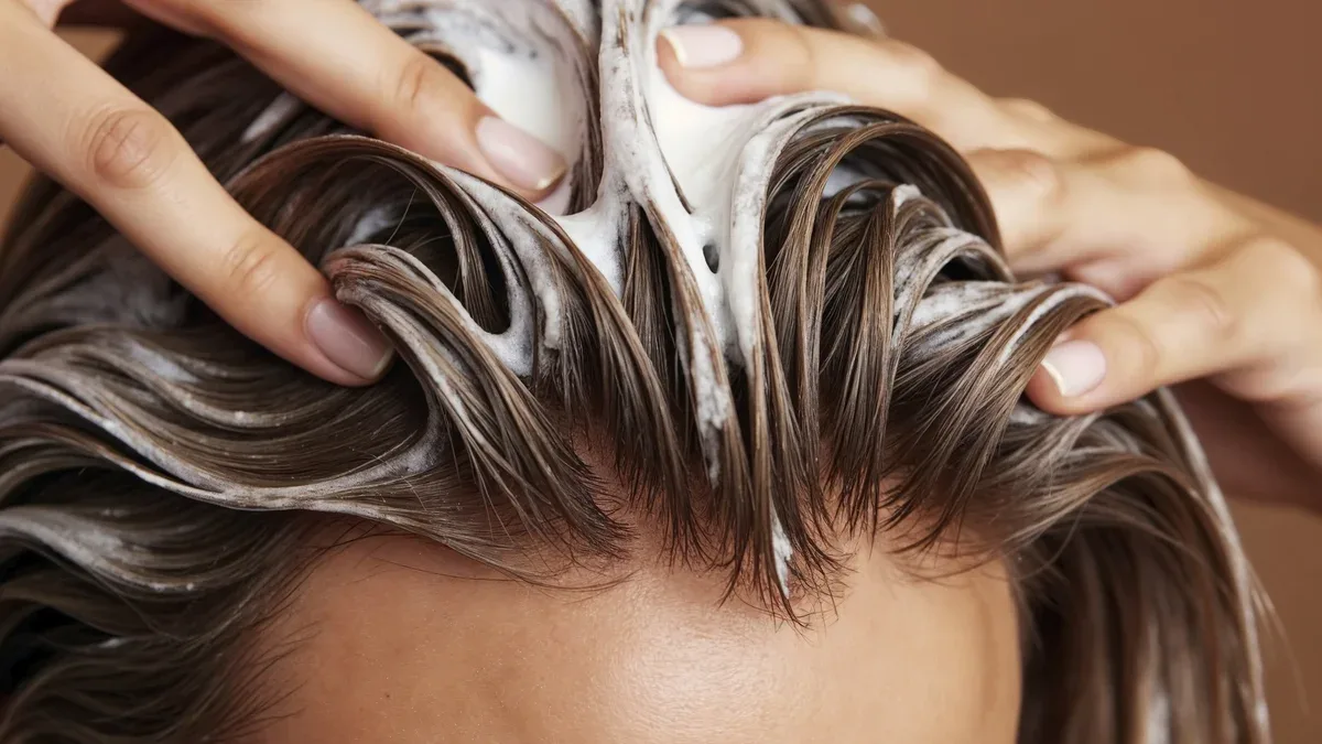 Une femme s'applique du shampooing sur ses cheveux