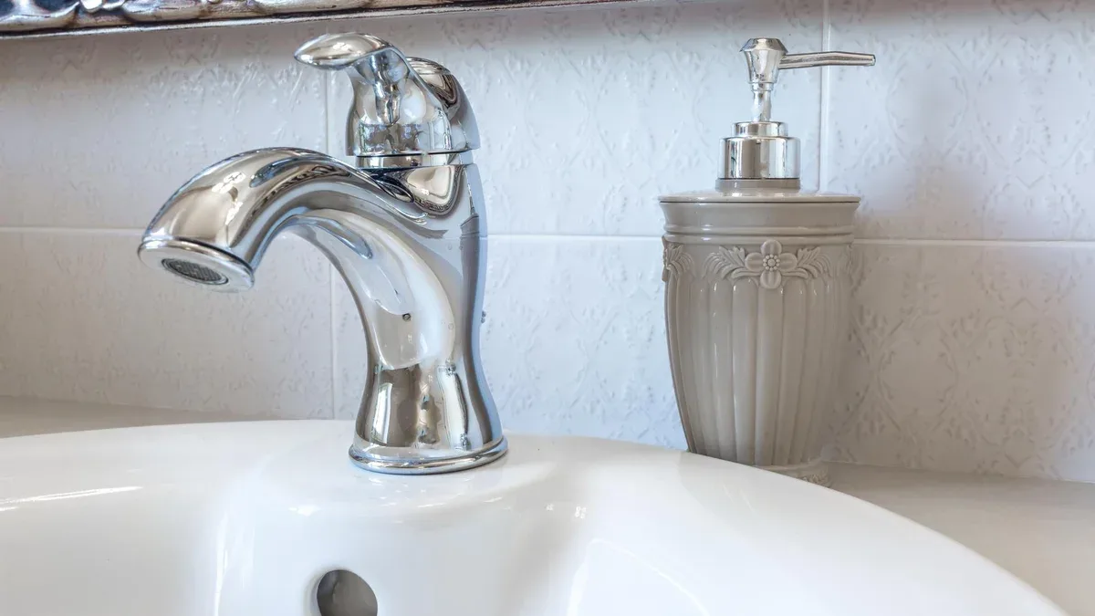 Distributeurs de savon et de shampoing sur l'évier du robinet d'eau avec robinet dans la salle de bains loft chère