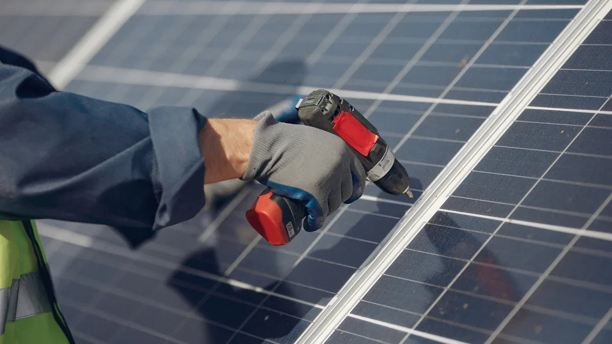 Un homme avec un casque blanc près d'un panneau solaire