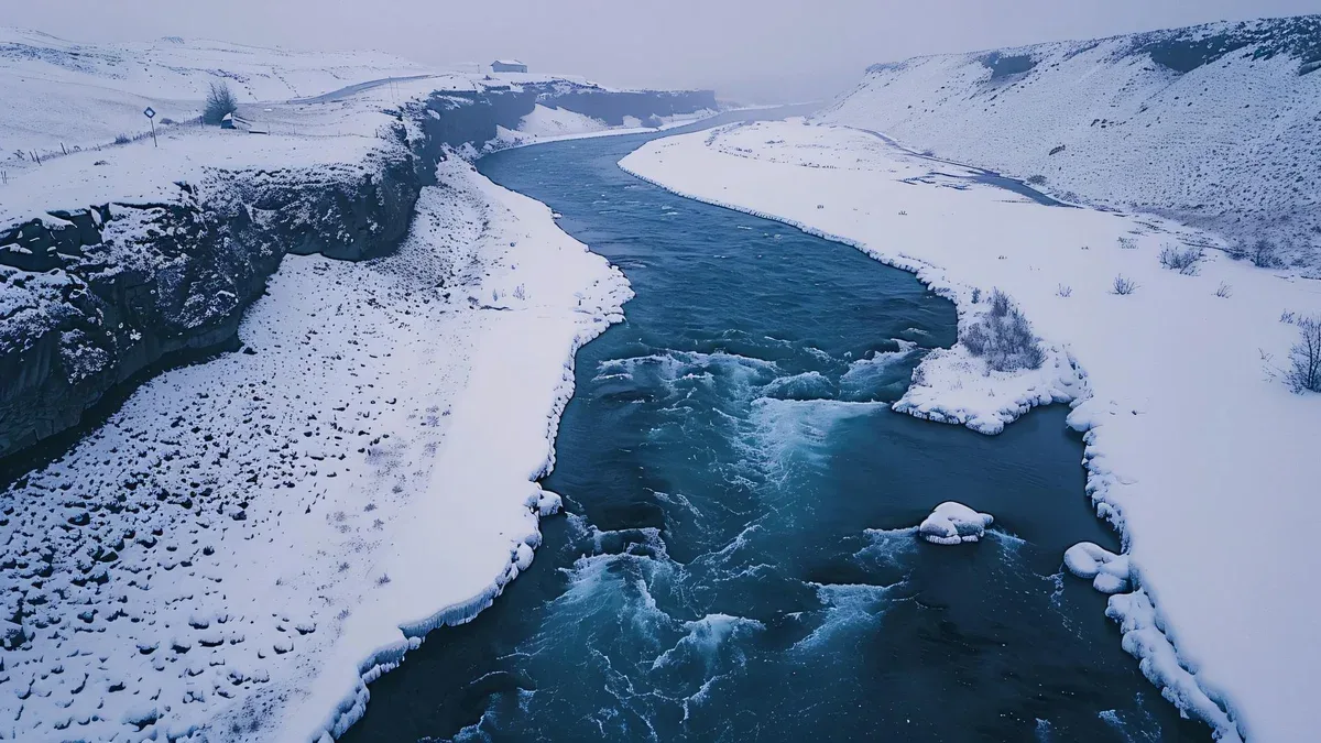 une rivière coule à travers une chaîne de montagnes couverte de neige