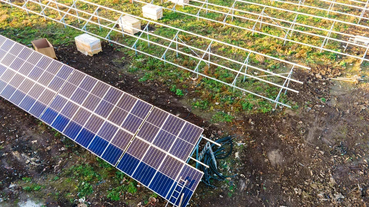 Vue aérienne de la centrale solaire en construction sur champ vert. Assemblage de panneaux électriques pour la production d'énergie écologique propre.