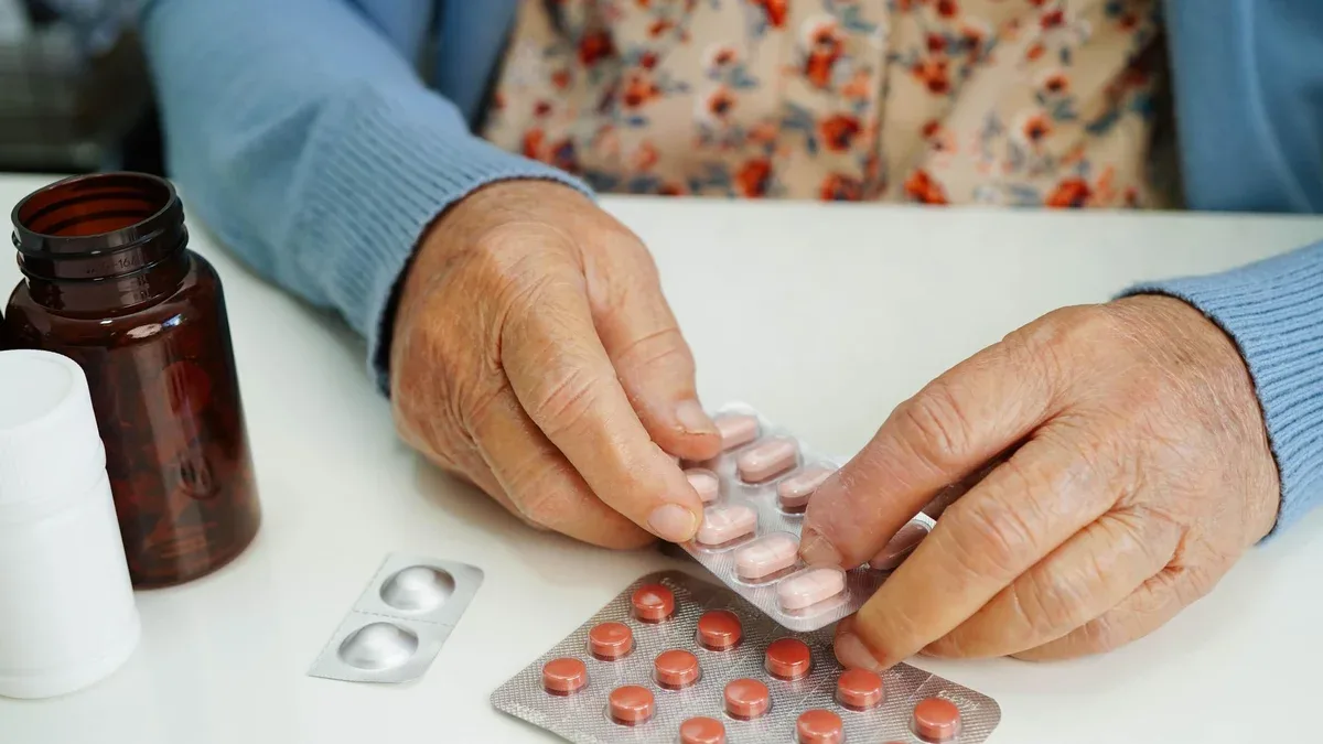 Une femme âgée asiatique tenant une pilule de médicament à la main est un médecin en bonne santé.