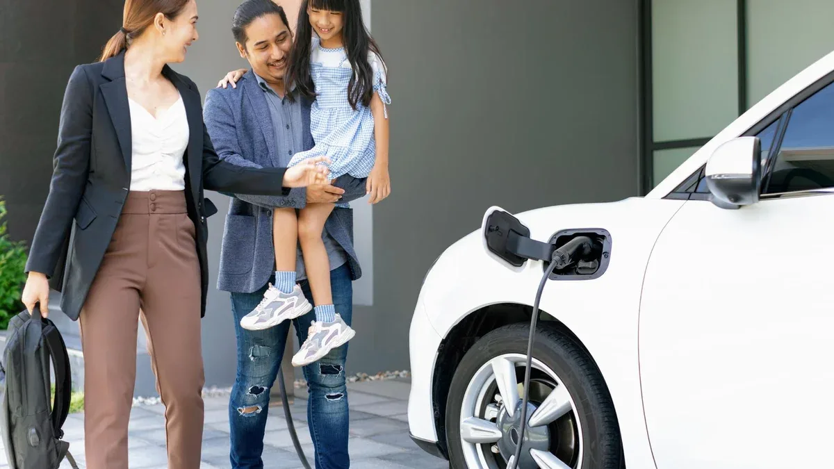 Jeunes parents progressistes et fille vivant dans une maison avec une voiture électrique