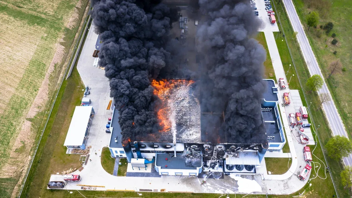 Vue aérienne d'un entrepôt industriel brûlé ou d'un bâtiment de centre logistique après un grand incendie avec une énorme fumée provenant du toit brûlé