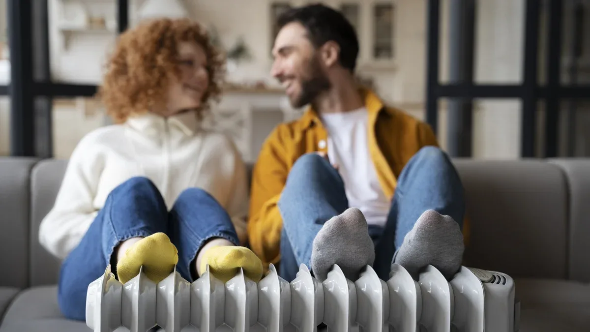 Couple de smiley plein coup se réchauffant près du radiateur